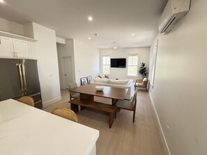 Open-concept kitchen and dining area with sleek cabinetry and a cozy entertainment setup.
