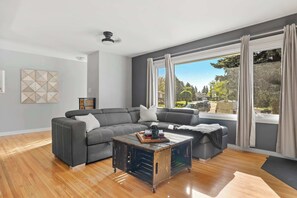 Lounge in comfort—Smart TV, plush couch, and park views.