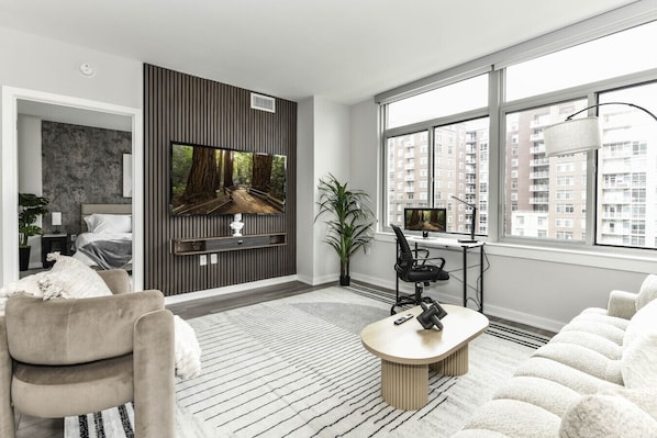 Chic and bright living room with cozy couch, flatscreen Tv and dedicated work station
