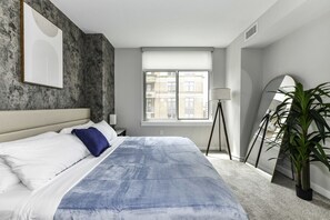 Bright, modern bedroom 1 featuring a king-size bed, pack n play crib and large windows that let in plenty of natural light.