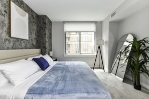 Bright, modern bedroom 1 featuring a king-size bed, pack n play crib and large windows that let in plenty of natural light.