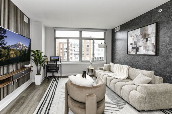 Chic and bright living room with cozy couch, flatscreen Tv and dedicated work station