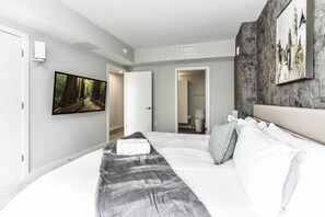 Bright, modern bedroom 1 featuring a king-size bed, pack n play crib and large windows that let in plenty of natural light.