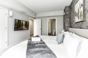 Bright, modern bedroom 1 featuring a king-size bed, pack n play crib and large windows that let in plenty of natural light.