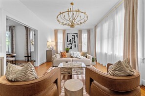 "Bright, elegant living space with designer touches, cozy seating, and floor-to-ceiling windows for a warm, welcoming vibe."