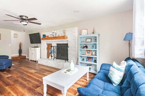 View from walking in from Front Door. Blue single-person futon, Electric Fireplace, Sectional, Roku TV, Games & Books in TV Console, plus Retro Arcade Game.