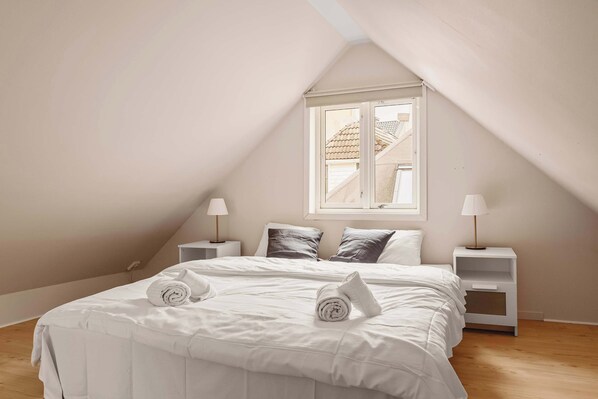 A warm and inviting loft bedroom with a slanted ceiling and natural light, perfect for a good night’s rest.