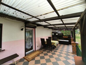 überdachte Terrasse mit Sitzmöbeln und Auflagenbox