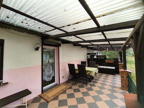 überdachte Terrasse mit Sitzmöbeln und Auflagenbox