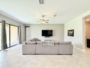 A large sectional sofa positioned toward a wall-mounted flat-screen TV.
