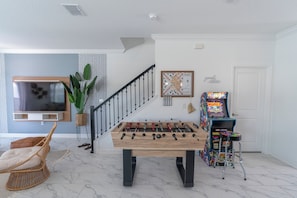 Enjoy endless entertainment in this corner with an arcade game and a foosball table, perfect for fun-filled moments!