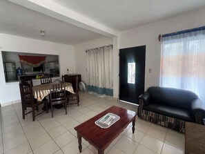 Sala (visto desde la entrada, centro de mesa, sillón, mesa comedor con 6 sillas, al fondo se ve la cocina)