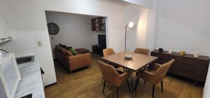 Comedor (mesa con 4 sillas, cocina integrada, planta de decoración, sala de entretenimiento al fondo)