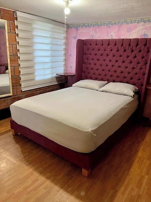 Habitación (vista desde la puerta, cama, cabecera, cortinas, espejo, lámpara)