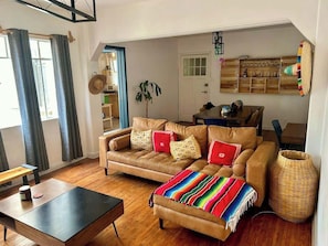 Sala (sofá, mesa de centro, banco largo, planta, sombreros de decoración, focos, lámpara, escritorio con silla, mesa con 4 sillas, cantina, cortinero)