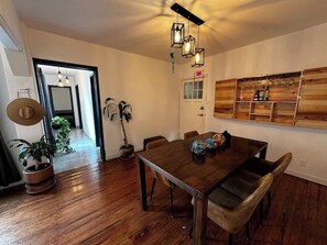 Sala (mesa con 4 sillas, sombreros de decoración, plantas, pasillo, focos, cantina con copas y licores)