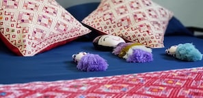 Cama (vista desde el pie de la cama, almohadas, muñecos de peluche)