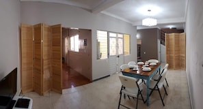 Comedor (visto desde la entrada, mesa con platos y sillas, biombos de madera, ventanas)