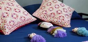 Cama (vista desde la cabecera, almohadas, muñecos de trapo)