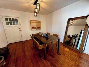 Sala vista desde el sofa (mesa con 4 sillas, espejo, cantina, focos, cofre, planta)