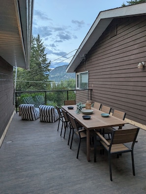 Deck between main house and bunkhouse with outdoor dining space and loungers