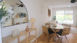 Bright and welcoming dining area complemented by a nearby mirror that enhances the natural light from the window and offers a spacious feel into the connected living space.