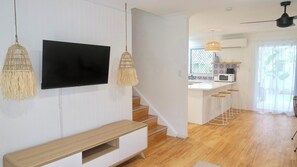 A modern TV setup, the staircase, and stylish kitchen.