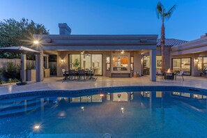 Backyard paradise includes a heated pool, 2 covered patios with dining tables, a TV and a gas fire pit.