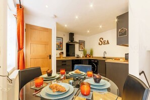 Bright Dining Area – Set for 4-6 with stylish tableware, this glass-top dining table invites you to slow mornings and lively mealtimes.