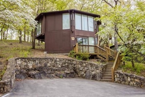 This modern elevated home offers a unique "treetop" living experience, blending seamlessly with the surrounding lush natural landscape. Multiple large windows allow for abundant natural light and scenic views, making this a bright and inviting retreat.
