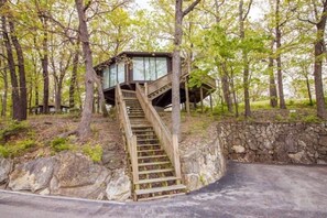 This modern elevated home offers a unique "treetop" living experience, blending seamlessly with the surrounding lush natural landscape. Multiple large windows allow for abundant natural light and scenic views, making this a bright and inviting retreat.