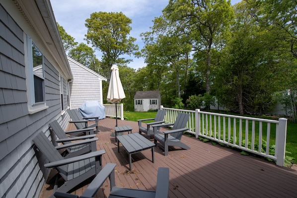 Furnished back deck with umbrella-shaded seating—perfect for outdoor meals and relaxing in the Cape breeze.