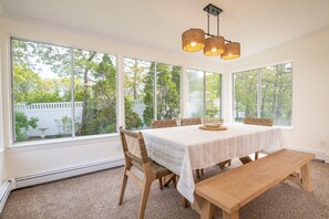 Sunlit dining room in the cozy sunroom—ideal for casual meals and board games with garden views.
