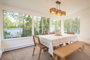 Sunlit dining room in the cozy sunroom—ideal for casual meals and board games with garden views.