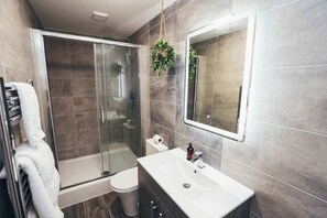 Shower room with tiled walls, storage shelves, and bright lighting