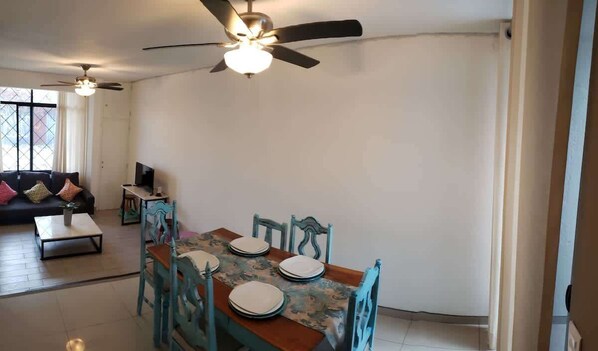 Cocina (vista desde las escaleras, mesa con sillas, ventana, sillones, televisión)