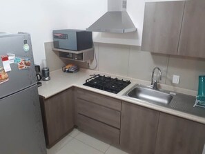 Cocina (vista desde la entrada, parilla, lavabo, mueble, campana, microondas, cafetera, refrigerador)