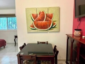 Mesa de madera con vidrio, sillas de madera, cuadro de sandias, vitrina de madera, decoraciones, televisión