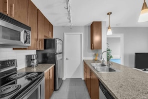 Sleek and functional kitchen featuring granite countertops, stainless steel appliances, and warm wooden cabinetry—perfect for cooking and entertaining in style.
