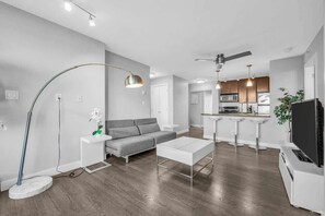 Modern and stylish open-concept apartment with sleek hardwood floors, contemporary furnishings, and a chic kitchen featuring stainless steel appliances—perfect for urban living.