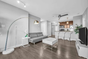 Modern and stylish open-concept apartment with sleek hardwood floors, contemporary furnishings, and a chic kitchen featuring stainless steel appliances—perfect for urban living.
