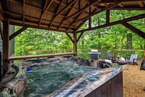 Spacious covered 7-person communal hot tub area surrounded by nature.