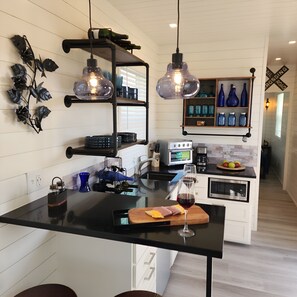 Fully-equipped modern kitchenette in luxury container home Fredericksburg TX - stove, refrigerator, wine glasses ready for Hill Country winery visits, railway-themed design