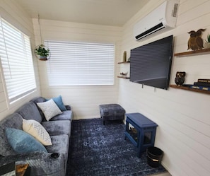 Cozy living area in luxury container home Fredericksburg - smart TV, plush seating, AC comfort for wine country guests exploring Texas Hill Country wineries and downtown attractions.
