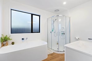 Main bathroom with freestanding tub and walk-in glass shower.