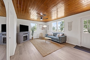 Bright and inviting living area with cozy sitting, large windows and smart TV.