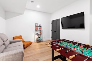 Lower-level gameroom with foosball, seating, a variety of games and puzzles, and a Smart TV for streaming