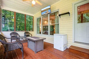 Unwind in the screened-in porch with a cool drink, a warm fire, and nature all around—TV above, forest views ahead, and comfort all around.
