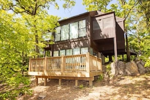 This modern elevated home offers a unique "treetop" living experience, blending seamlessly with the surrounding lush natural landscape. Multiple large windows allow for abundant natural light and scenic views, making this a bright and inviting retreat.