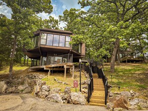 This modern elevated home offers a unique "treetop" living experience, blending seamlessly with the surrounding lush natural landscape. Multiple large windows allow for abundant natural light and scenic views, making this a bright and inviting retreat.